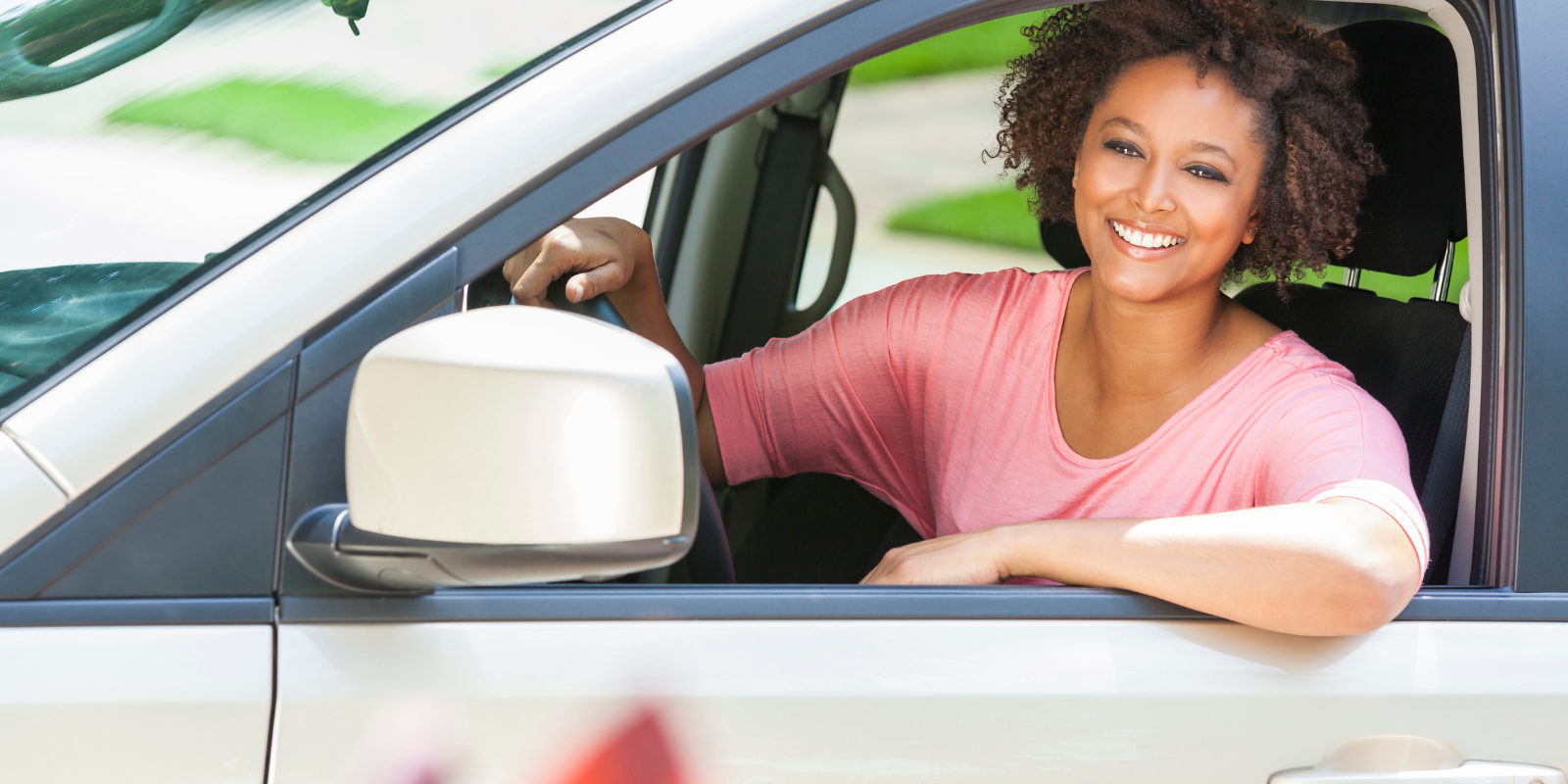 a woman sitting in the drivers seat of a car smiling